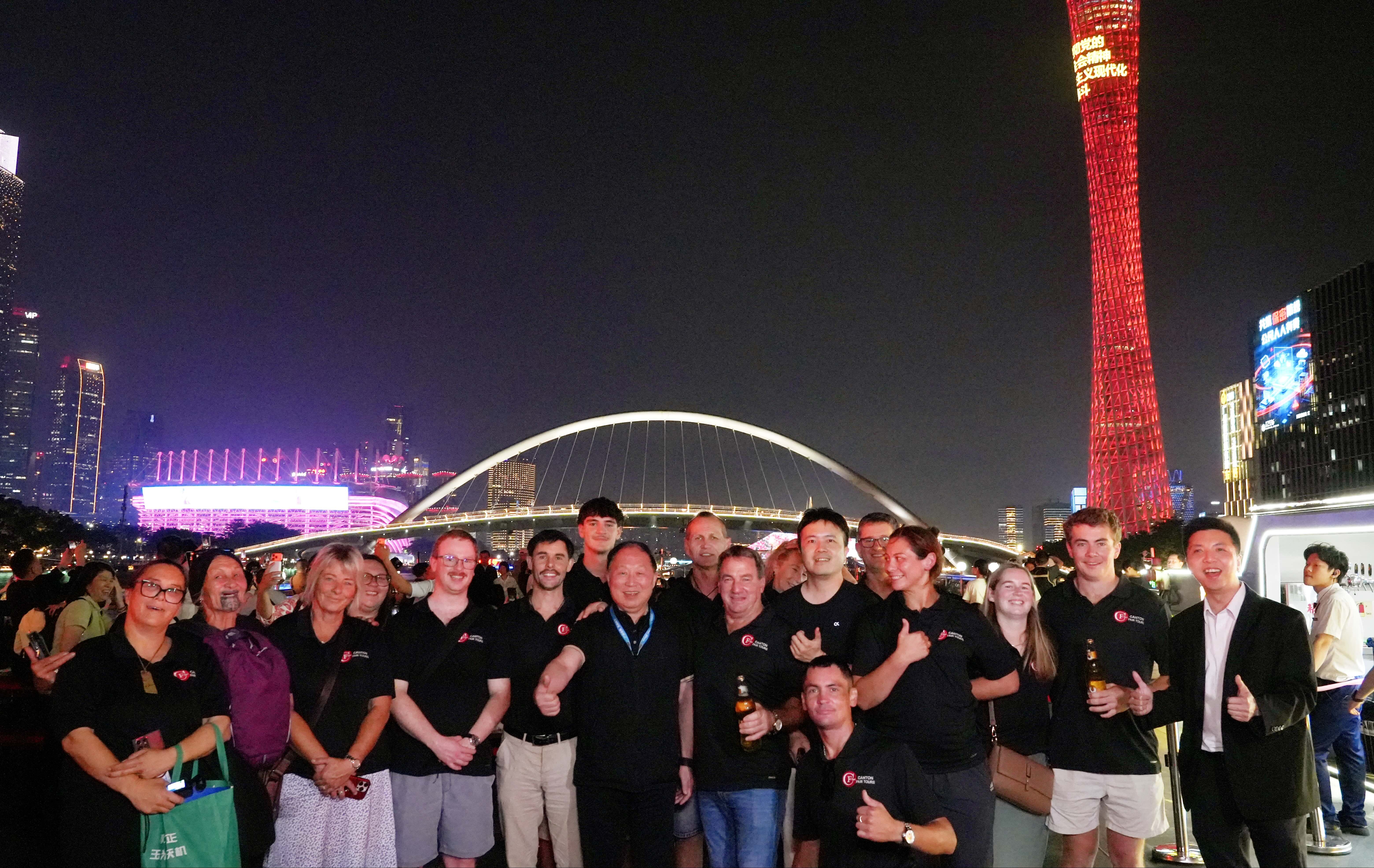 Delegation photographed at night beside a bridge and the illuminated Canton Tower during a Guangzhou city exchange evening.